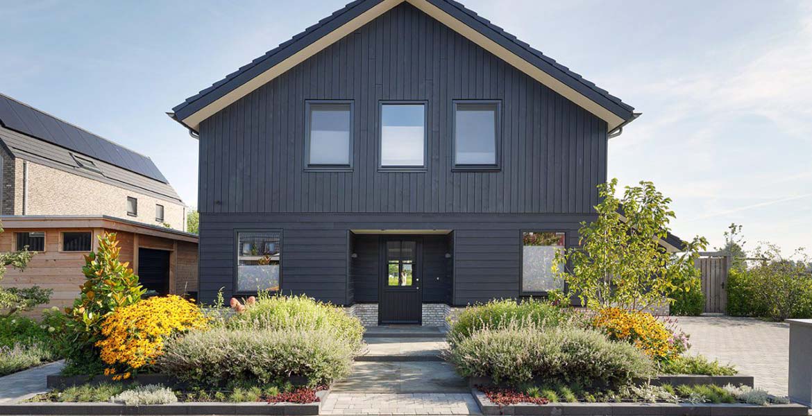 De voorzijde van een schuurwoning met zwarte houten panelen. 